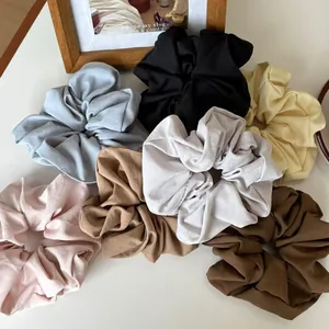 Flat lay of colorful matte fabric scrunchies in seven various Morandi pastel shades