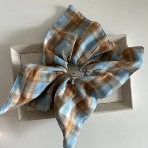 Close-up of a blue and brown plaid scrunchie with a soft brushed texture on a beige box