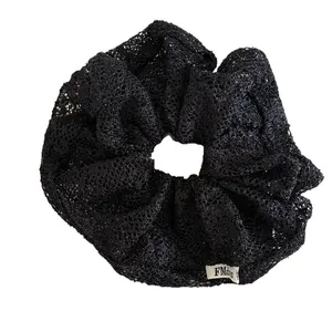 Eleganter schwarzer Spitzen-Scrunchie mit Stickerei und weißem Markenetikett
