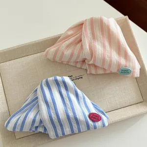 Detailed view of striped fabric hair claw with delicate woven texture and brand tag