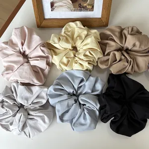 Set of six colorful satin silk scrunchies in pastel tones on a white minimalist surface