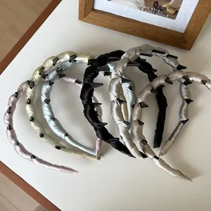 Détail d'un serre-tête en satin tissé avec mini-clips aux couleurs Morandi et fini soyeux