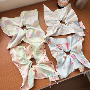 Close-up of four colorful bow scrunchies with cute animal patterns on a wooden table