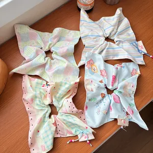 Set of four pastel bow scrunchies with cute cartoon patterns on a wooden surface