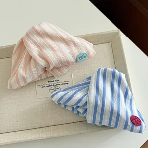 Detail of pink and blue striped fabric hair clips with logo tags on a display tray