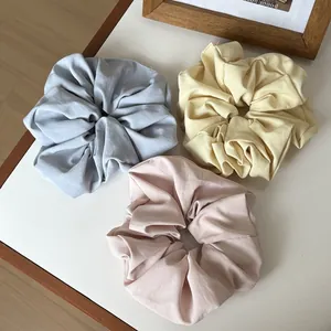 Three-piece set of matte fabric scrunchies in light blue, yellow, and dusty pink shades