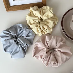 Detailed close-up of three matte pastel scrunchies in blue, yellow, and pink fabric