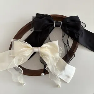 Detailed view of satin and organza bow hair clips with white pearl pendants