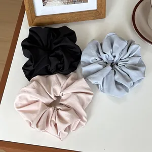 Detailed view of oversized matte scrunchies in black, light grey, and soft pink colors