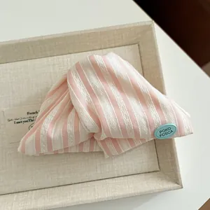 Detail of pink and white striped fabric hair claw with delicate lace texture and logo