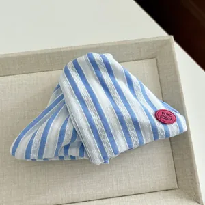 Detail of blue and white striped fabric hair clip with a pink rubber brand logo tag