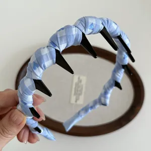 Detail of blue and white plaid fabric headband featuring inner wave tooth hair combs