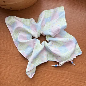 Macro detail of large pastel scrunchie with patchwork patterns and beaded ties