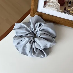Detail of dusty blue fabric scrunchie with soft matte texture and ruffled design