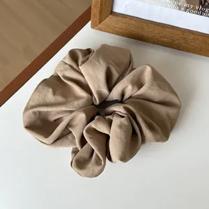 Detail of earthy brown matte fabric scrunchie with natural soft pleated texture