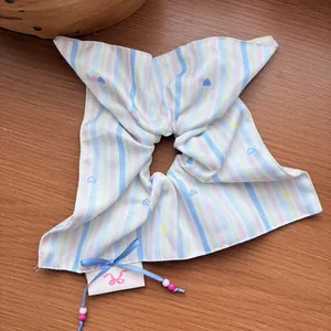 Detail of striped hair scrunchie with heart patterns, beads, and a large bow design