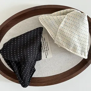 Close-up of polka dot fabric hair clips in black and beige on a round wooden tray