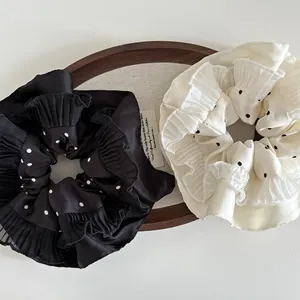 Detail of black and white polka dot oversized pleated scrunchies on wooden tray