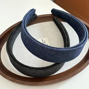 Detail of wide denim headbands in navy and charcoal on a rustic linen wooden tray