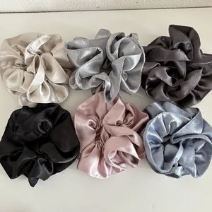 Detail of six assorted pearlescent satin hair scrunchies in elegant neutral colors