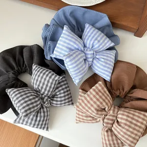 Dettaglio di grandi elastici per capelli con fiocco a scacchi in cotone blu, nero e marrone