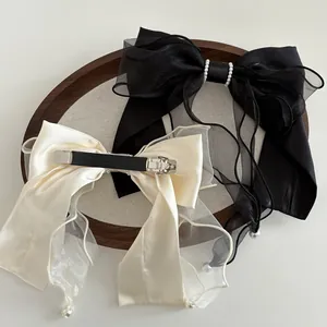 Elegant satin and mesh bow hair clips with pearls on a wooden tray for women