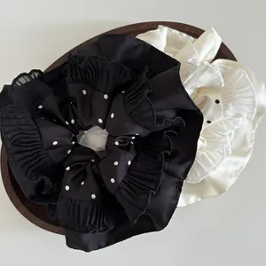 Close-up of polka dot satin scrunchies with pleated edges on a rustic wooden tray