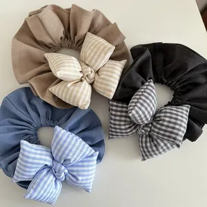 Tre elastici scrunchie giganti con fiocco e motivi a quadri in beige, blu e grigio
