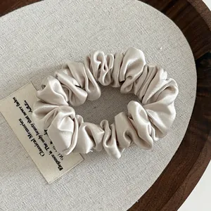 Detailed texture of champagne satin scrunchie fabric with elegant pleated folds