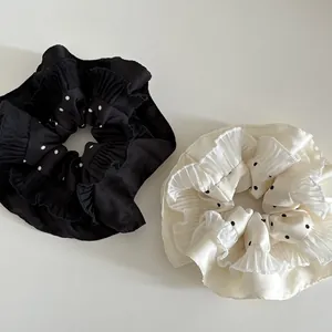 Close-up of black and cream satin polka dot scrunchies with multilayered ruffle edges