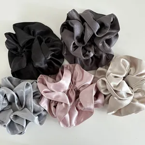 Macro detail of five assorted silk satin scrunchies in neutral elegant color tones