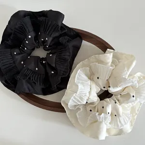 Close-up of elegant polka dot hair scrunchies with pleated edges on a wooden tray
