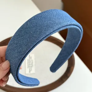 Detail shot of wide blue denim fabric headband with layered texture on wooden tray