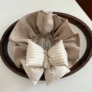 Dettaglio di uno scrunchie con fiocco a scacchi e texture imbottita su vassoio in legno