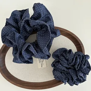 Dettaglio del set di elastici per capelli a pois blu scuro su un vassoio di legno elegante