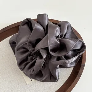 Detailed view of dark grey premium satin scrunchie with silk texture on wooden tray