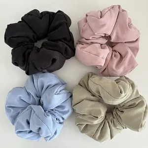 Detailed set of four oversized puffy scrunchies in black, pink, blue, and olive green