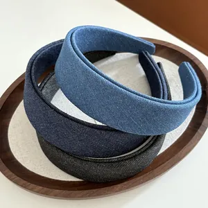 Three-piece denim fabric headbands in light blue, dark blue and grey on a wooden tray
