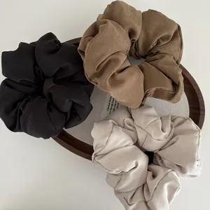 Detailed view of large fluffy scrunchies in black, brown, and beige textured fabric