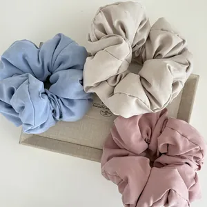 Detailed texture of cotton fabric scrunchies in blue, beige, and pink tones