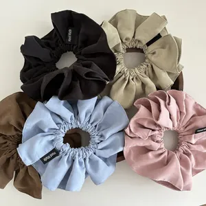 Detailed texture of assorted matte fabric scrunchies with Hand Made woven label tags
