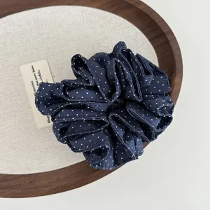 Dettagli dell'elastico per capelli blu navy a pois su sfondo di lino vintage