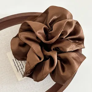 Detail of premium heavy satin oversized scrunchie in dark brown with rich silk texture