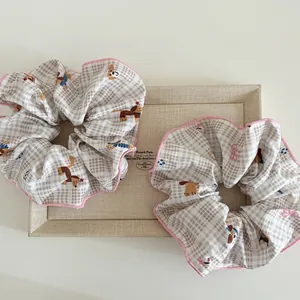 Detalle de coleteros con estampado de perro, bordes cosidos en rosa y textura de cuadros