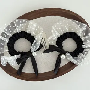 Detailed close-up of retro polka dot mesh scrunchie with satin bow and faux pearl detail