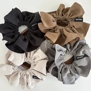 Detail of four matte scrunchies in neutral tones with hand made fabric labels