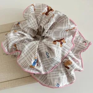 Detalle del coletero de cuadros beige con dibujos de perritos y bordes rosas cosidos