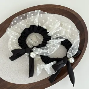 Detail of two French vintage hair scrunchies with white polka dot mesh, pearls and bows