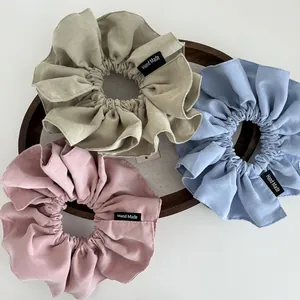 Detail of oversized matte fabric scrunchies in pastel colors on a wooden tray