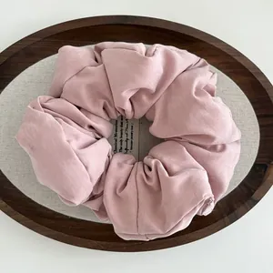 Close-up of pink puffy cotton scrunchie texture and soft pleats on rustic wooden tray